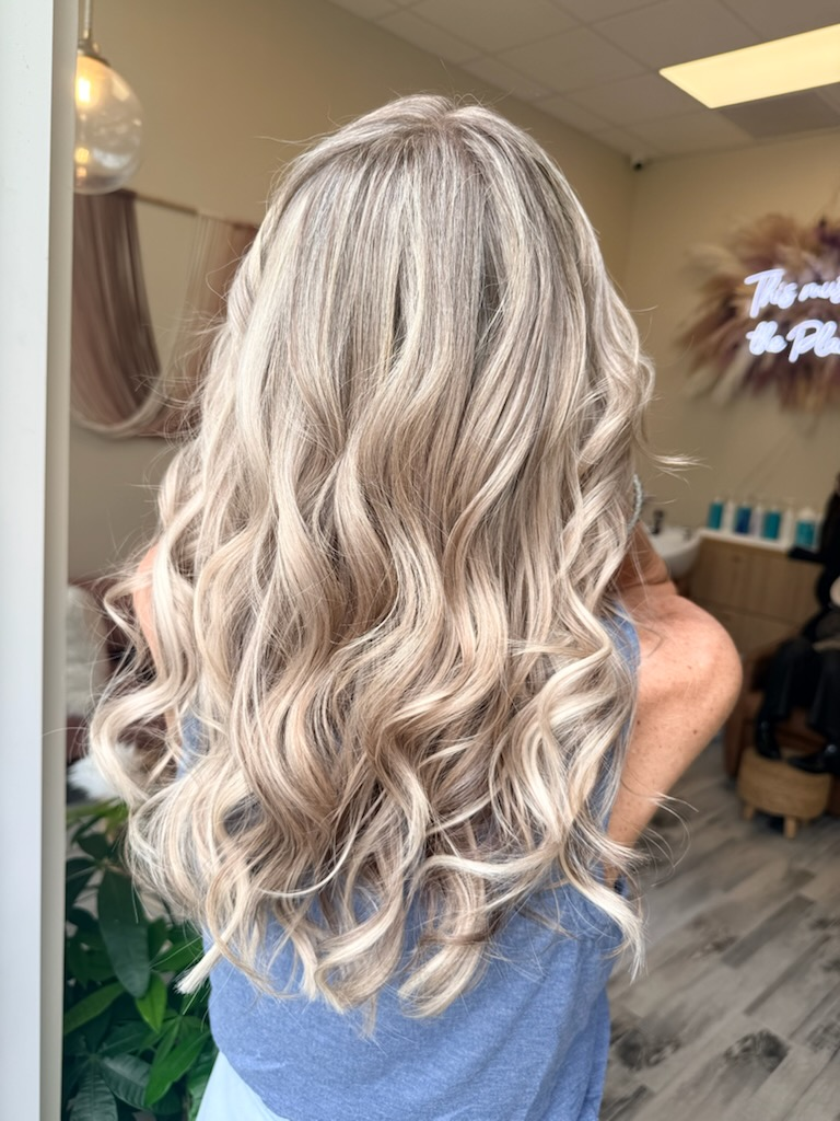 Long blonde hair styled in soft curls with dimensional highlights